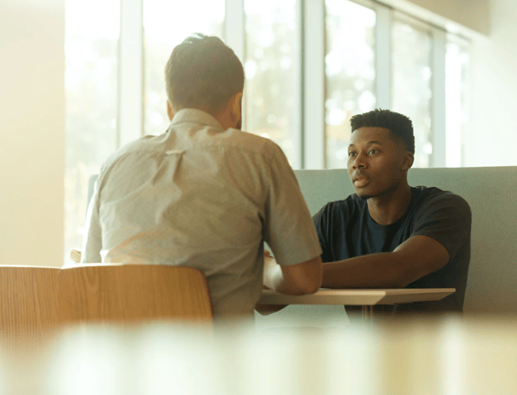 two people sitting in front of each other and talking