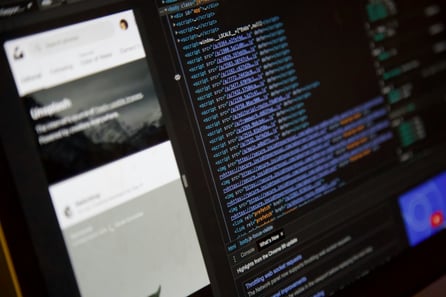 Close-up of a computer screen displaying HTML and JavaScript code alongside a web browser preview