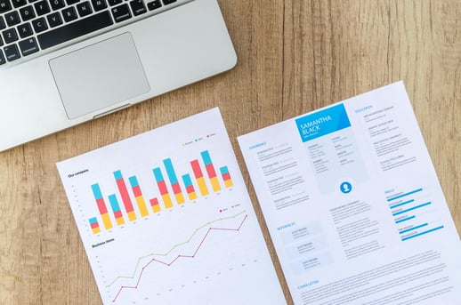 Clean, one-page resume layout next to performance charts and a laptop, illustrating the importance of clarity and impact in professional resumes.