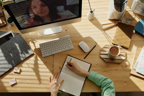 Student taking notes during a virtual internship meeting, illustrating remote work-based learning in action.
